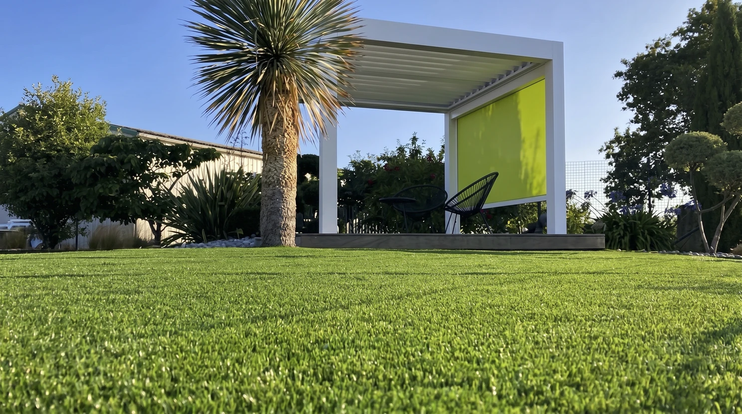 Jardin ext&eacute;rieur moderne avec pelouse en gazon synth&eacute;tique vert vif au premier plan