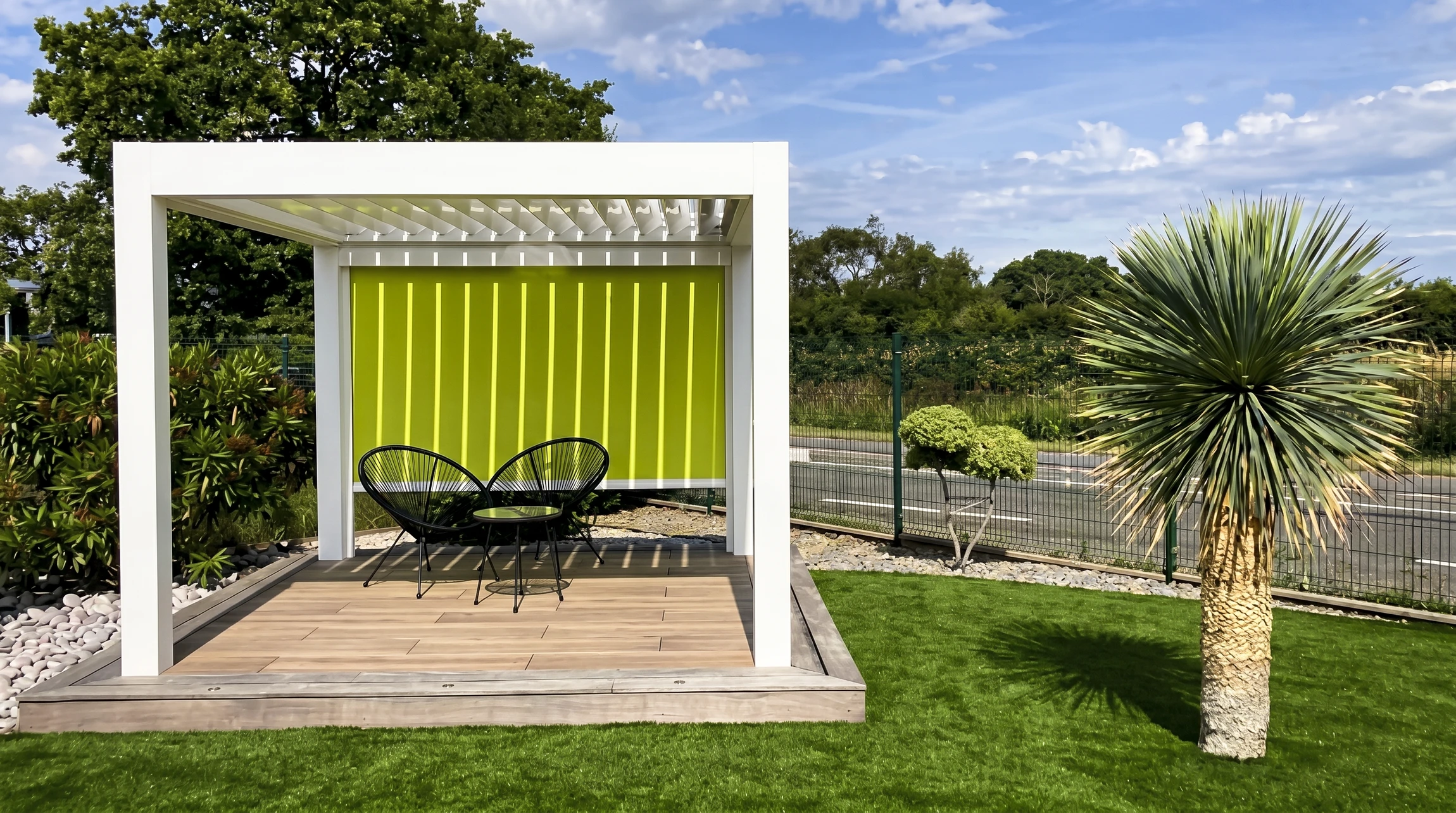 Pergola bioclimatique blanche à lames orientables, installée sur une terrasse en bois composite
