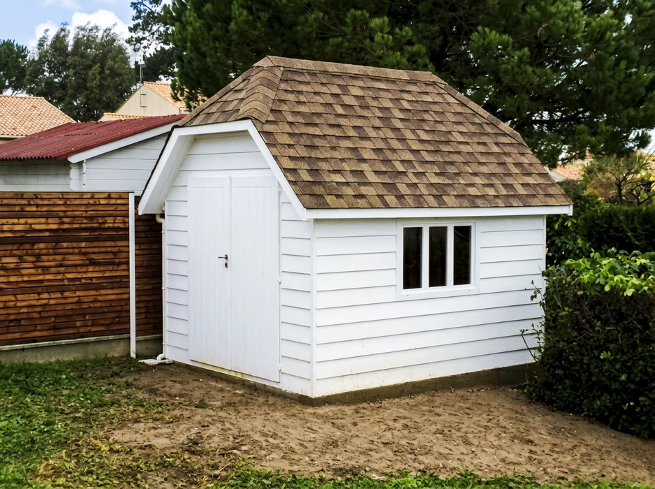 Abri de jardin extérieur, bardage bois blanc horizontal, toiture à quatre pans en bardeaux d'asphalte brun