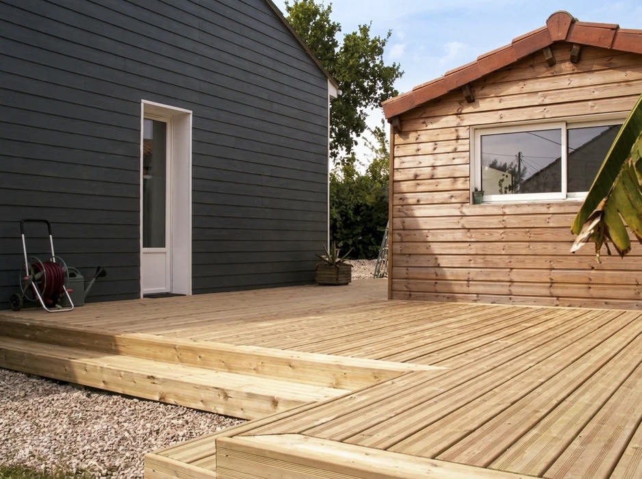 Terrasse en bois neuve, construction extérieure entre une maison à bardage gris anthracite et un chalet en bois naturel