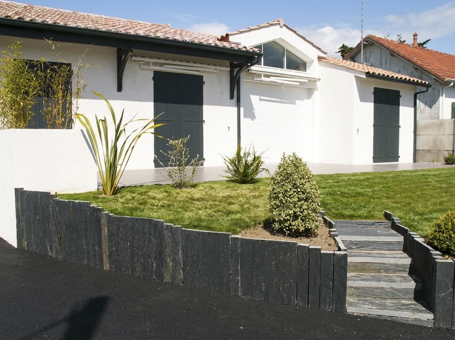 Jardin contemporain devant une maison blanche avec volets gris anthracite
