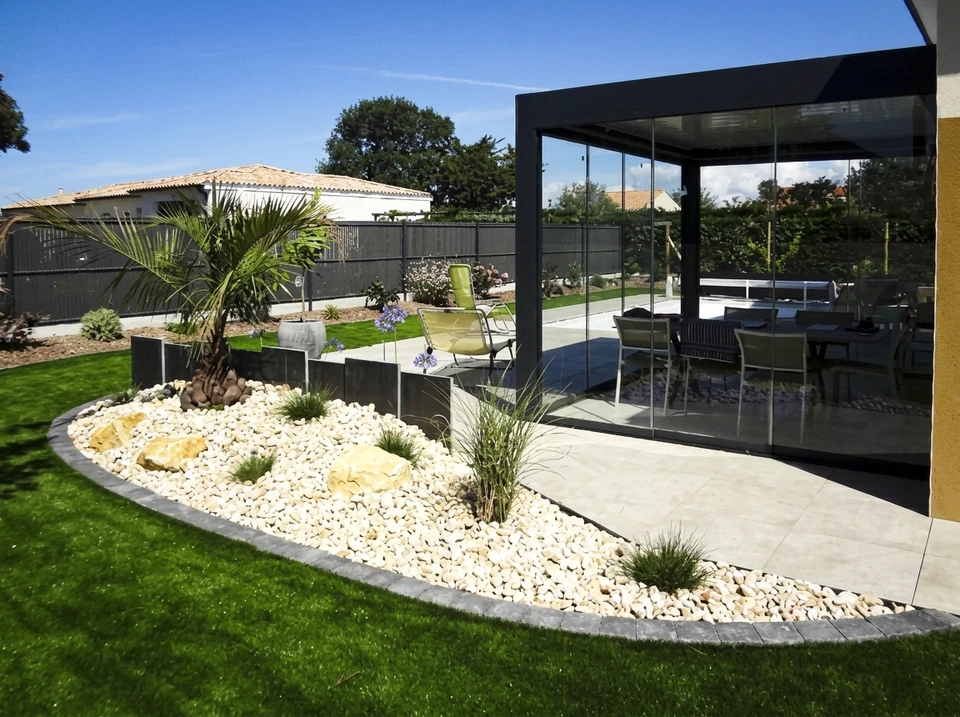 Terrasse extérieure dallée en ardoise grise, clôturée par des panneaux composites WPC (Wood Plastic Composite) à lames horizontales, teinte teck clair