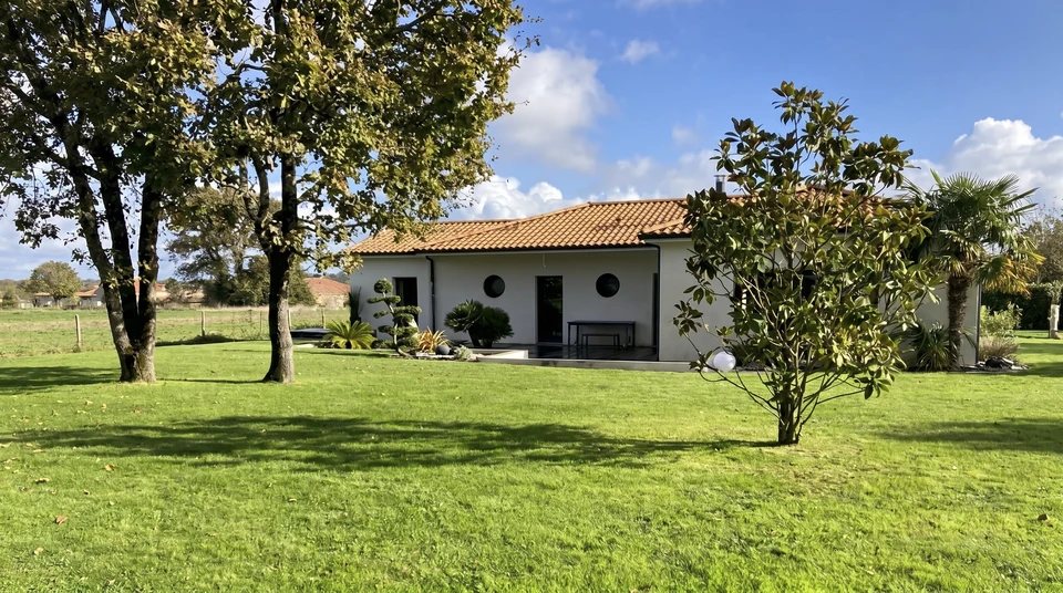 Jardin résidentiel avec pelouse verte entretenue, massifs de fleurs colorées incluant bougainvilliers roses, plantations en bacs et bordures paysagères